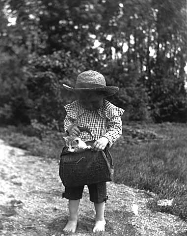 Child with kitten in purse. Photo by Louis Enstrom.